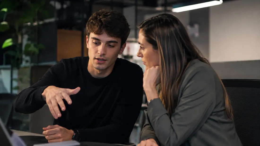 Two colleagues collaborating at a laptop in an office
